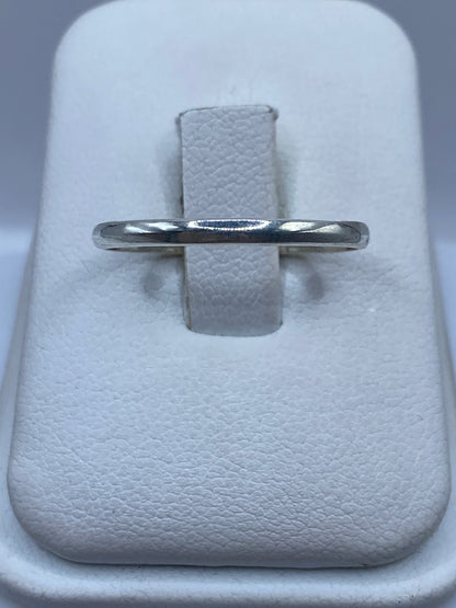 Anillo banda de plata pulida minimalista sobre fondo blanco