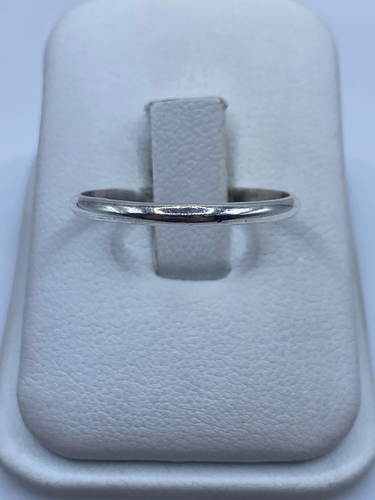 Anillo de plata banda lisa minimalista en la mano de una mujer, pulido espejo