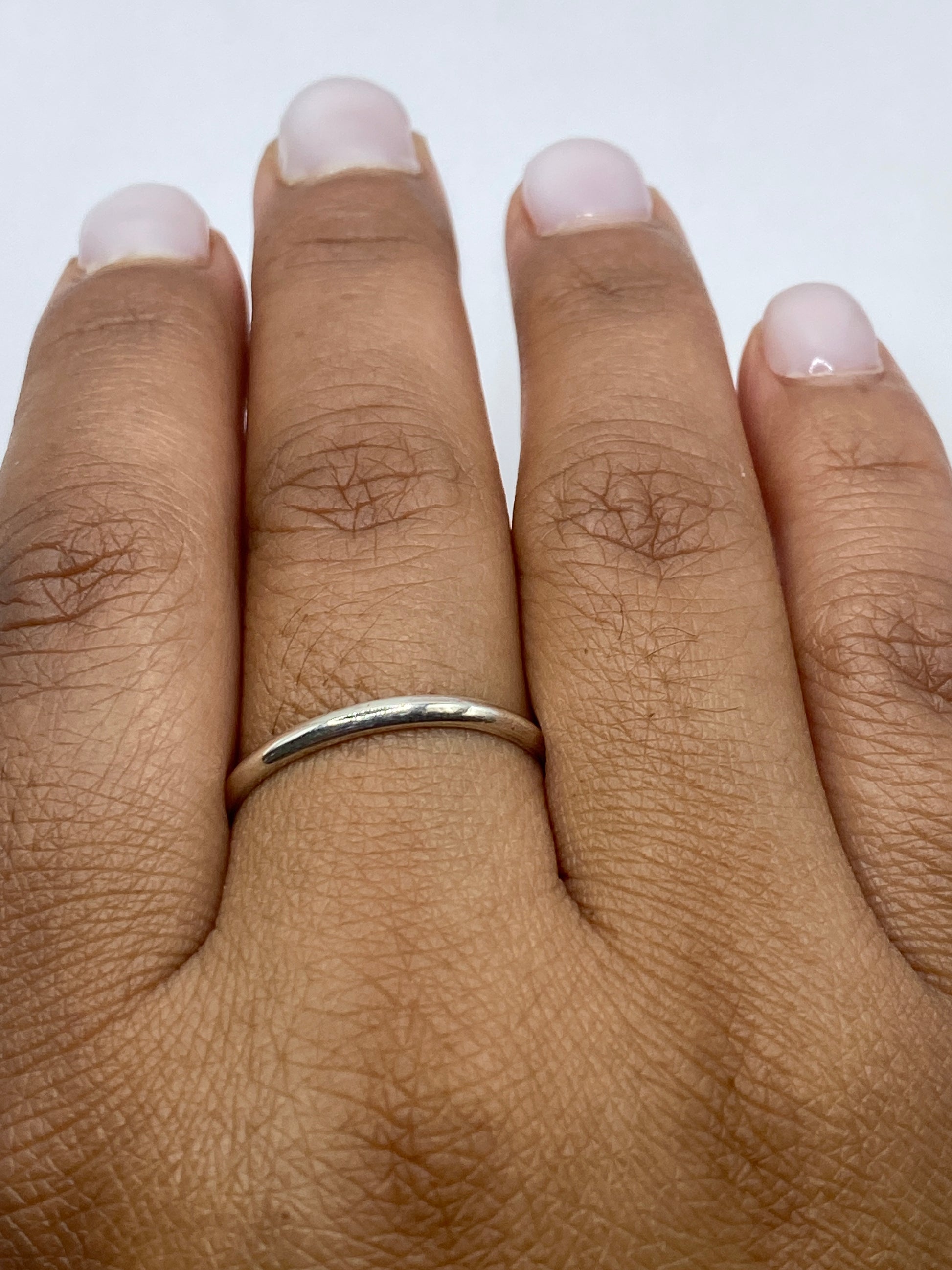 Anillo de plata pura banda lisa sobre fondo blanco, visión desde arriba
