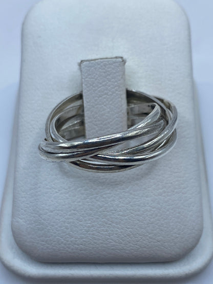 Anillo de plata con tres bandas entrecruzadas pulidas, vista frontal en joyero blanco