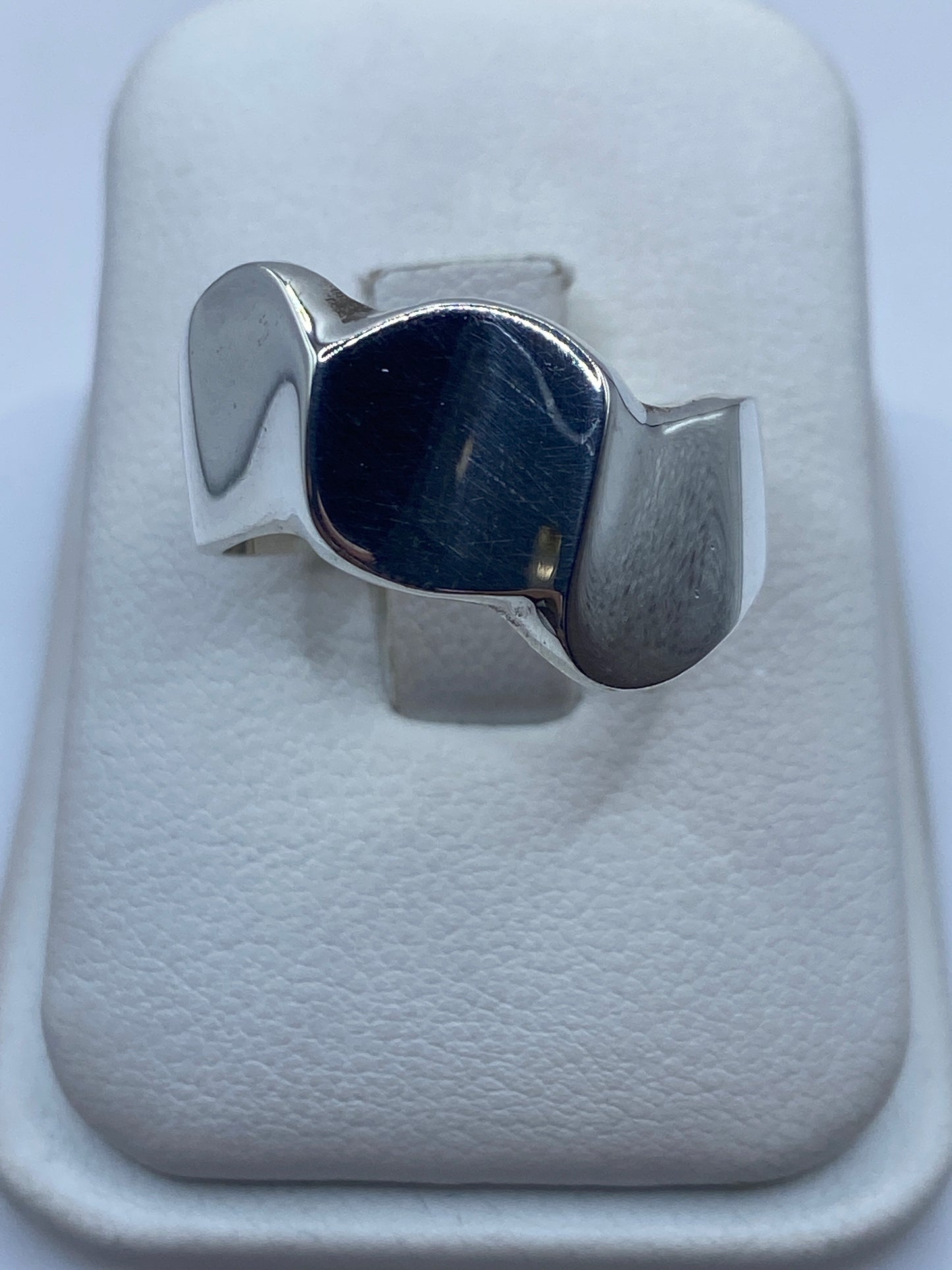 Anillo de plata geométrico minimalista sobre fondo blanco, vista frontal