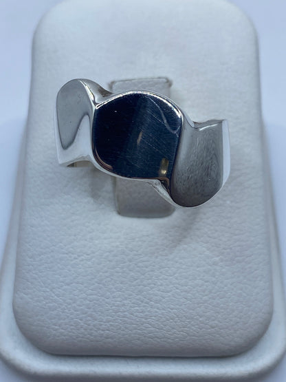 Anillo de plata geométrico minimalista sobre fondo blanco, vista frontal