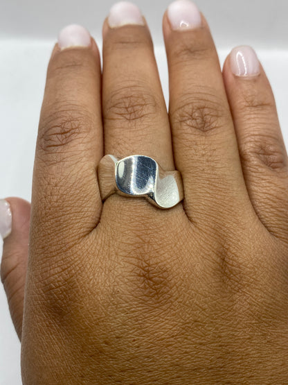 Anillo geométrico sobre superficie gris metalizada, acabado espejo y satinado