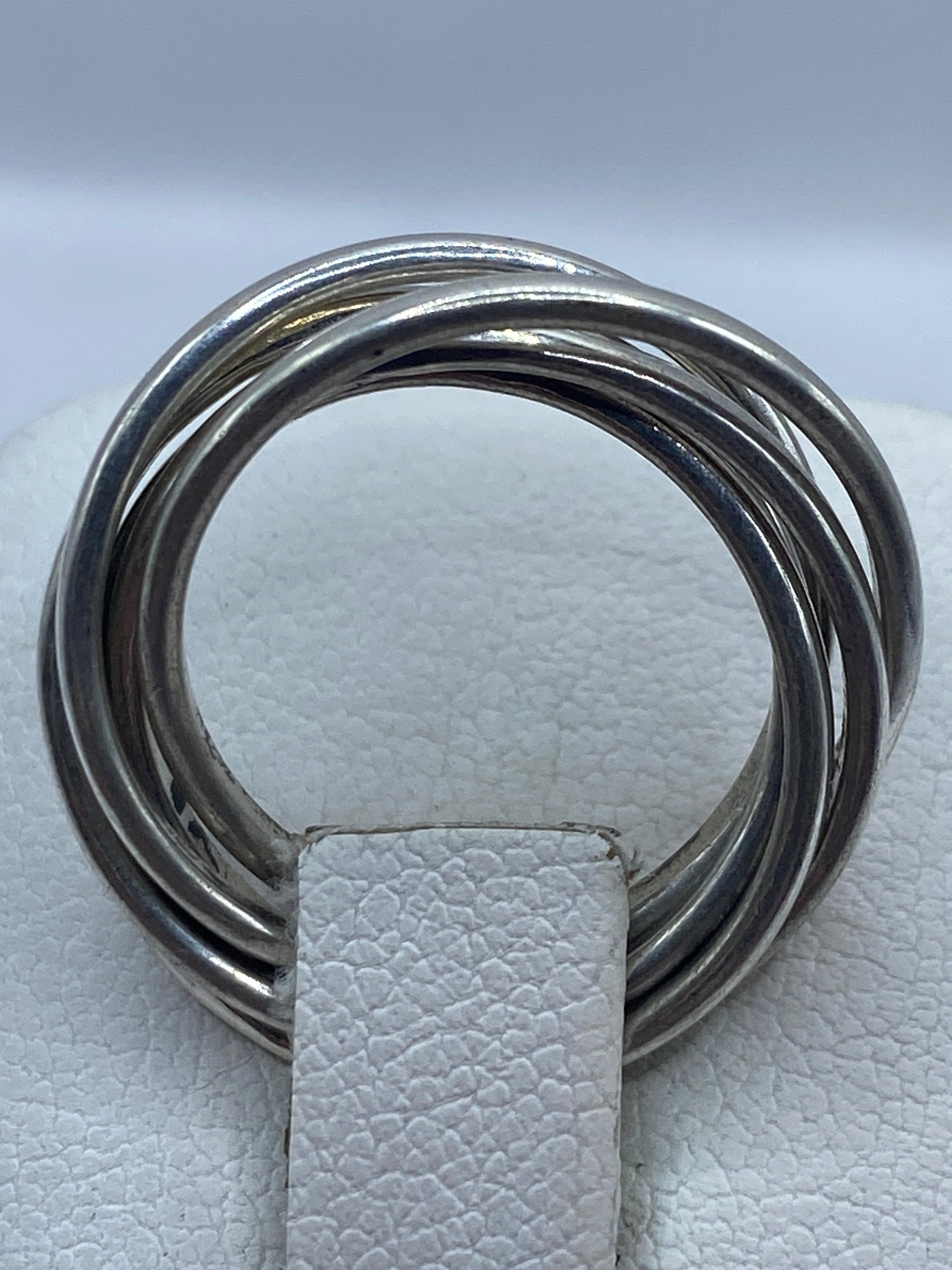 Anillo minimalista de bandas cruzadas en la mano con acabado espejo brillante