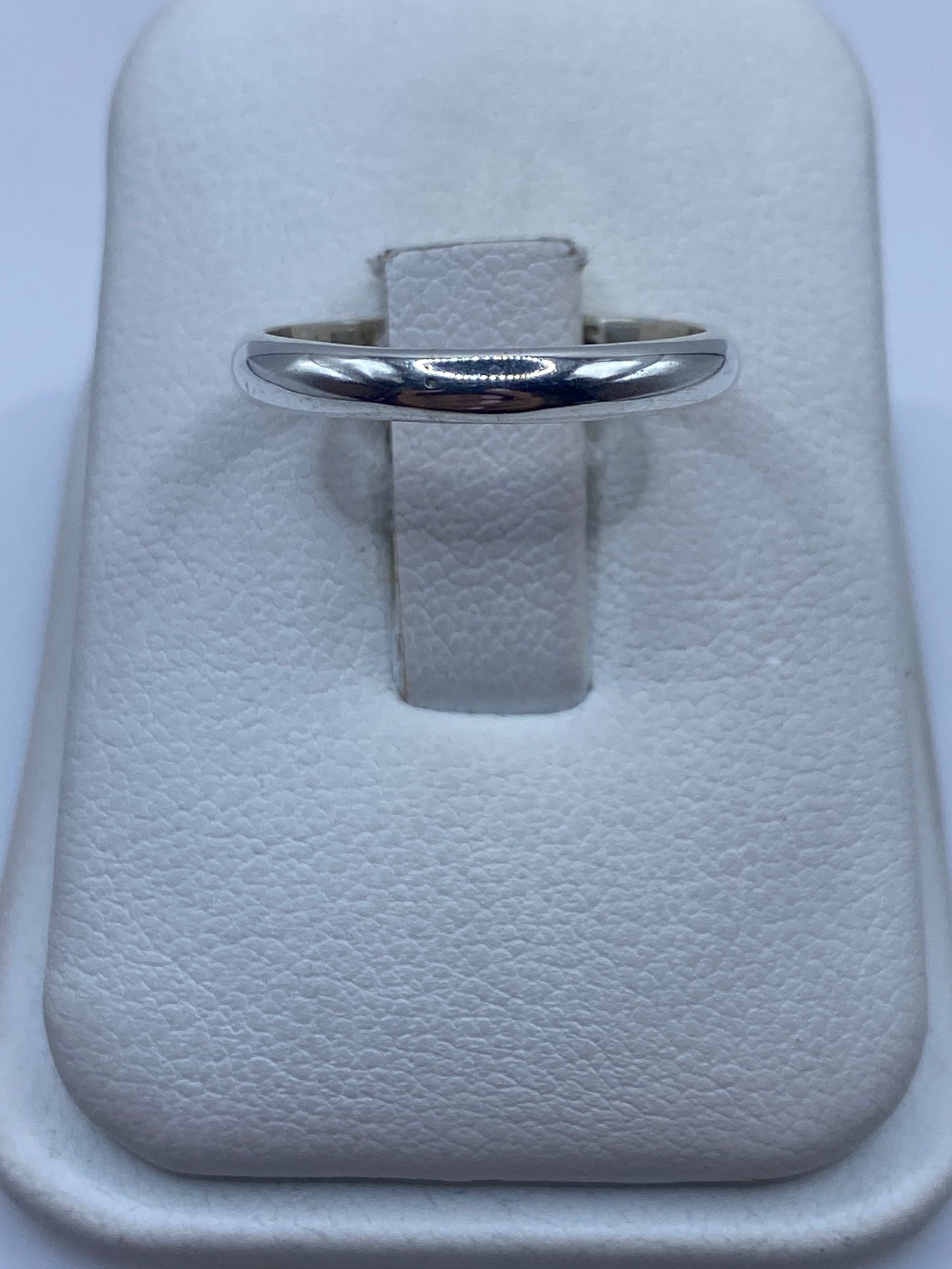 Anillo de plata banda pulida minimalista en la mano de una mujer