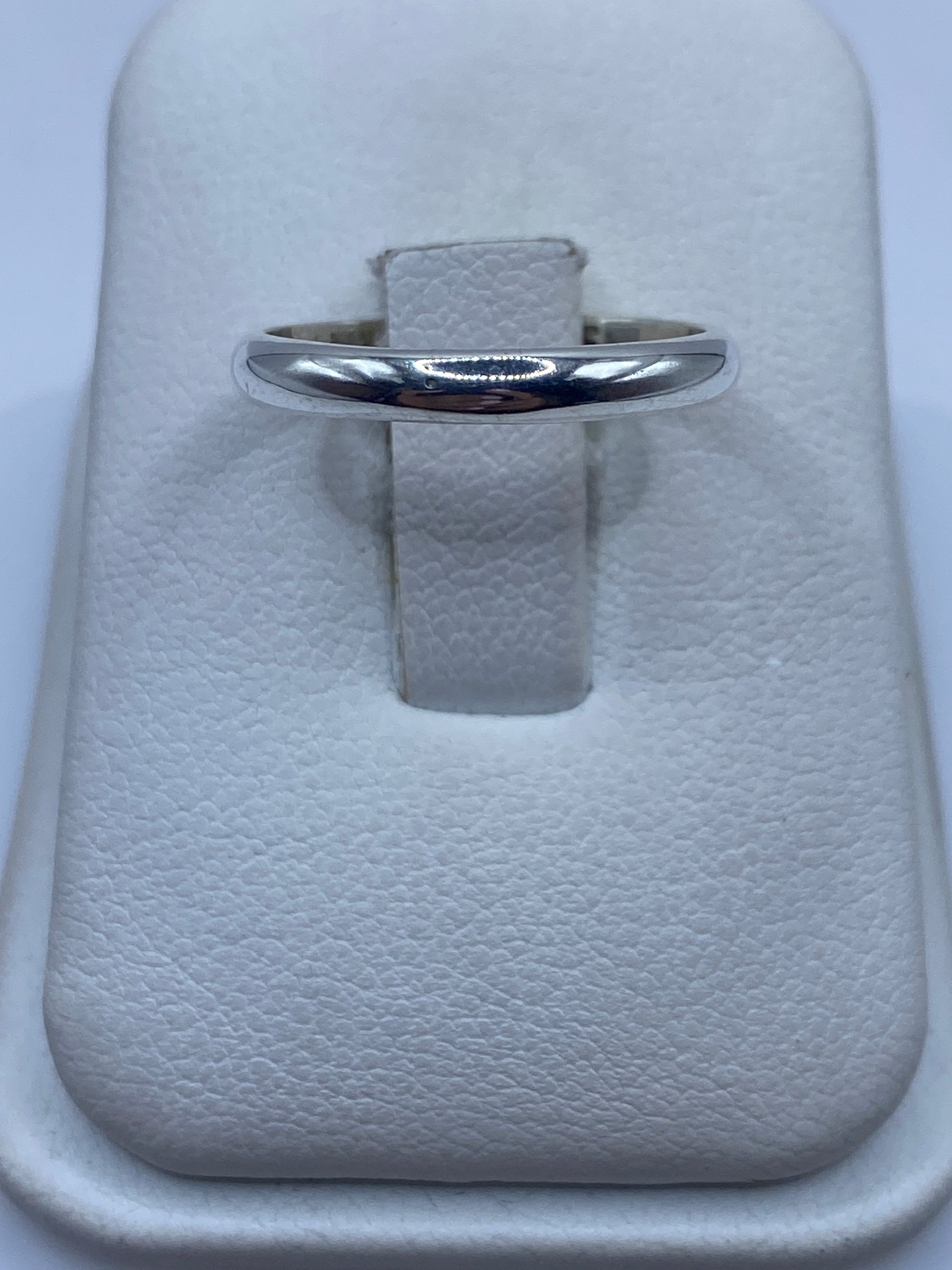 Anillo de plata banda pulida minimalista en la mano de una mujer