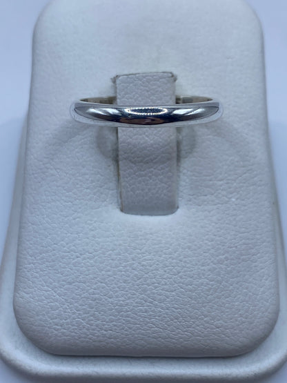 Anillo de plata banda pulida minimalista en la mano de una mujer