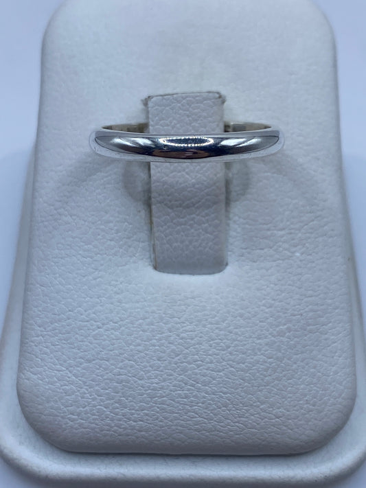 Anillo de plata banda pulida minimalista en la mano de una mujer