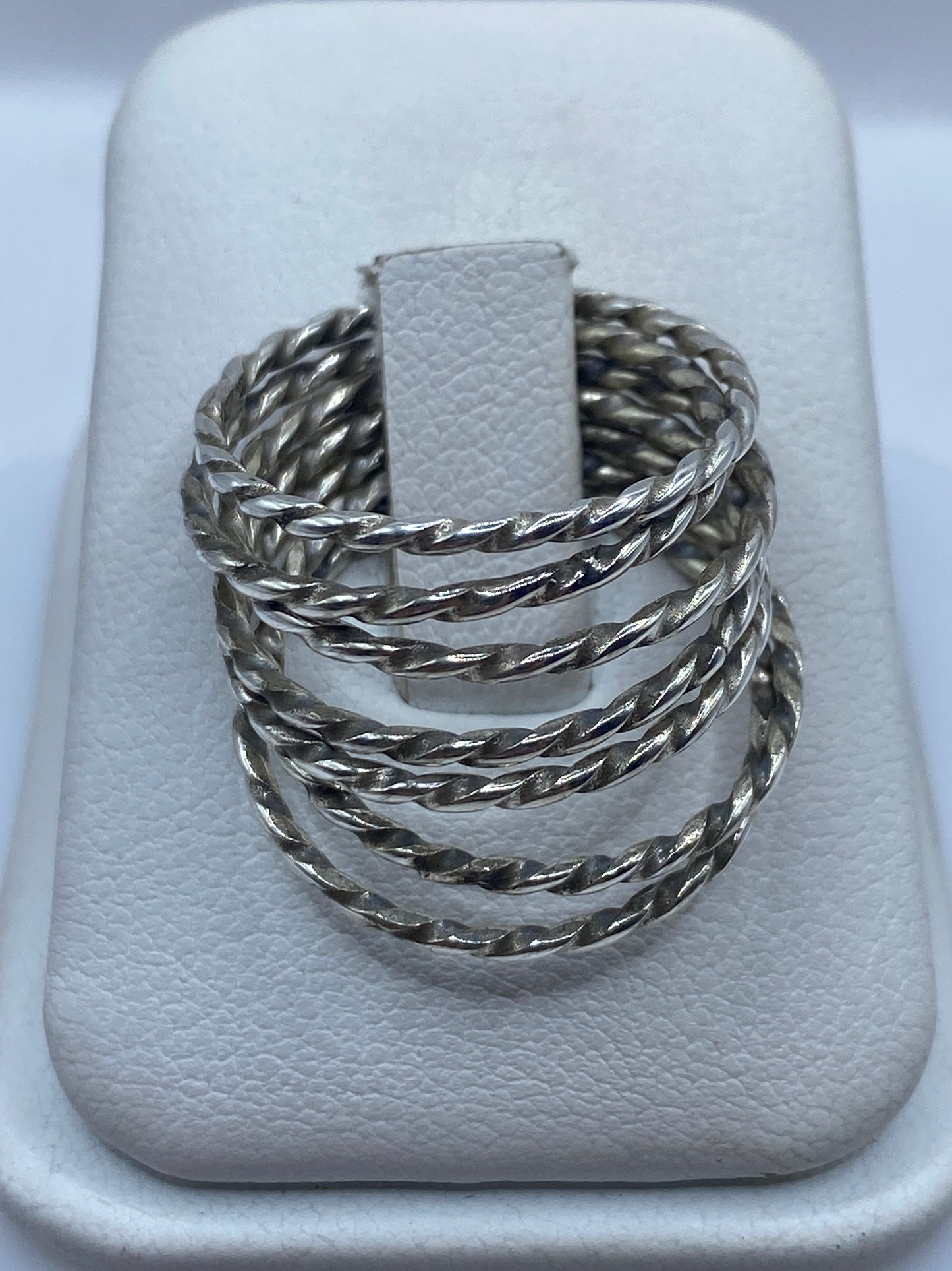 Anillo de plata con eslabones retorcidos tejidos a mano, mostrado en dedo