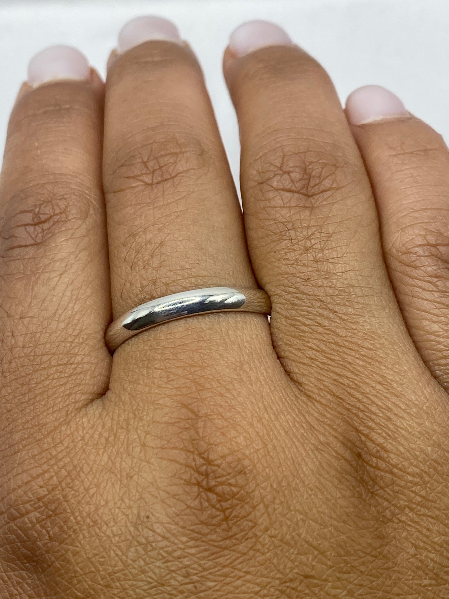 Anillo de plata sobre fondo blanco, vista lateral que muestra el ancho y pulido de la banda