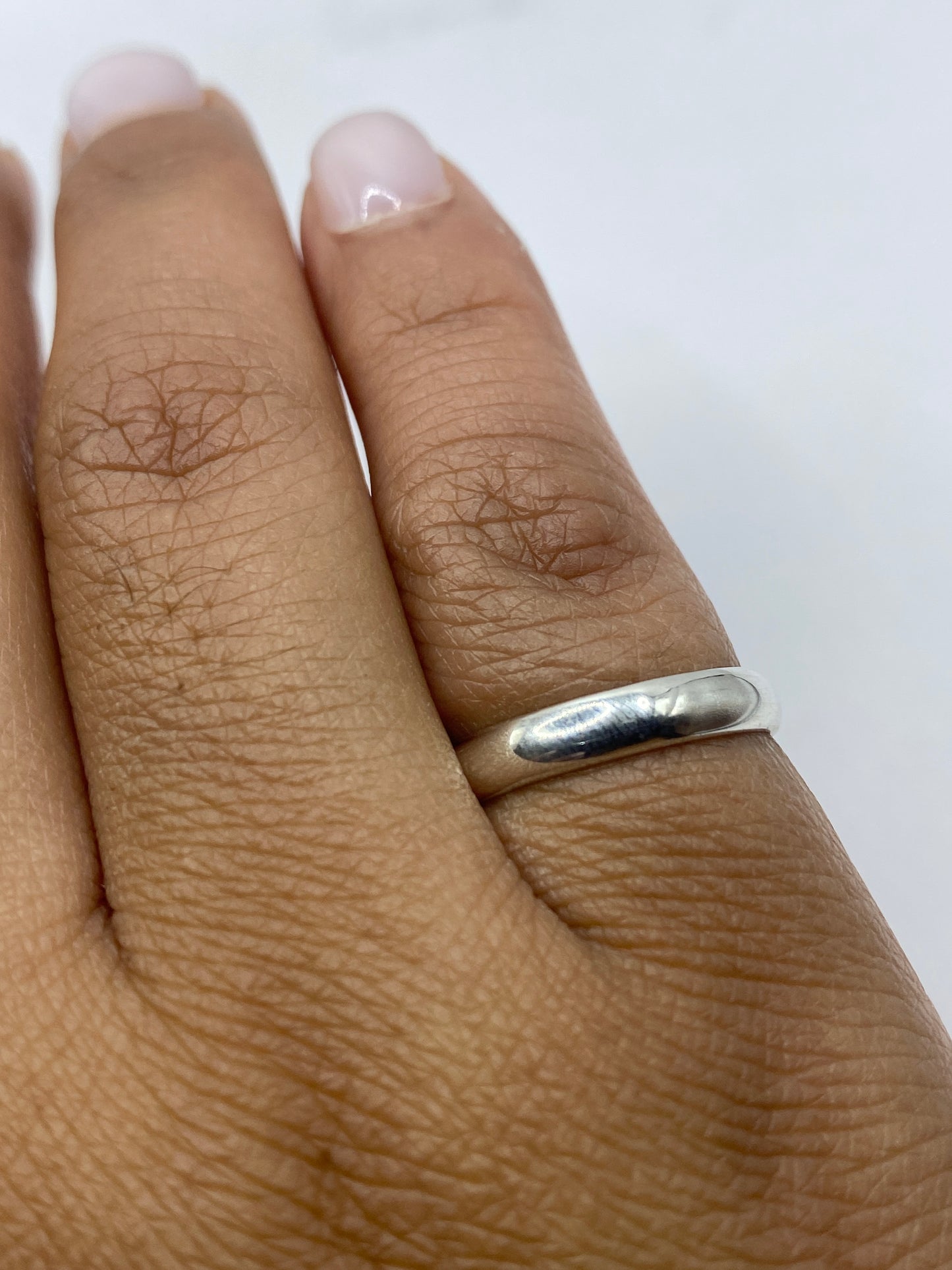 Anillo banda sobre superficie blanca, detalle del sello .925