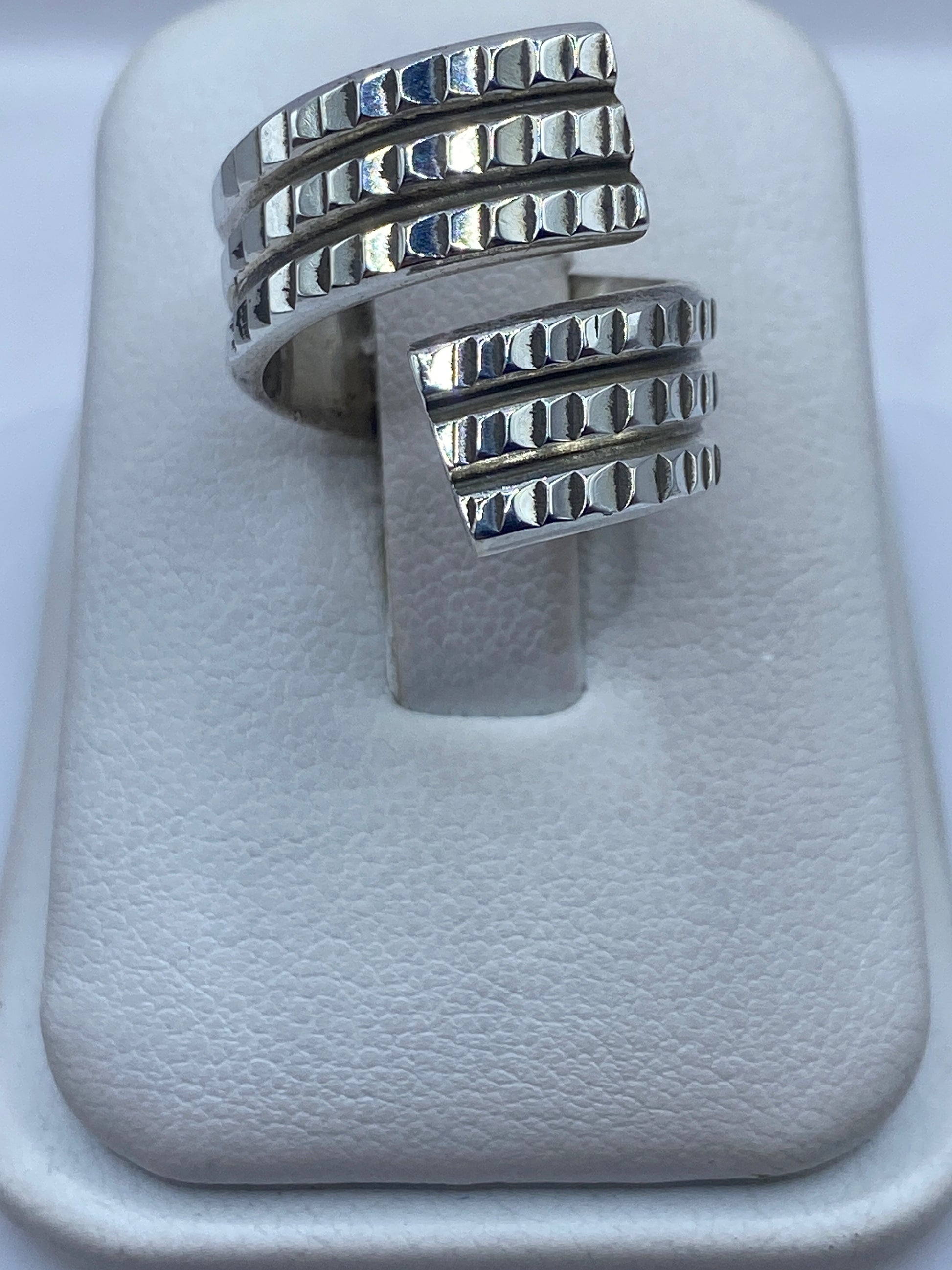 Anillo ajustable de plata con textura geométrica en relieve, vista desde arriba
