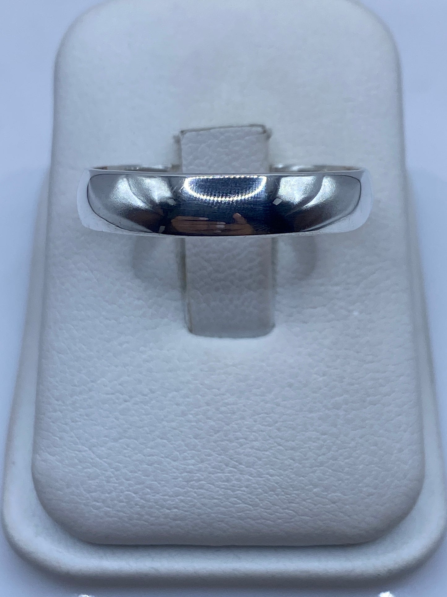 Anillo de plata minimalista pulido visto de frente, posado en estuche blanco