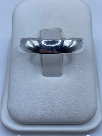 Anillo de plata minimalista pulido visto de frente, posado en estuche blanco