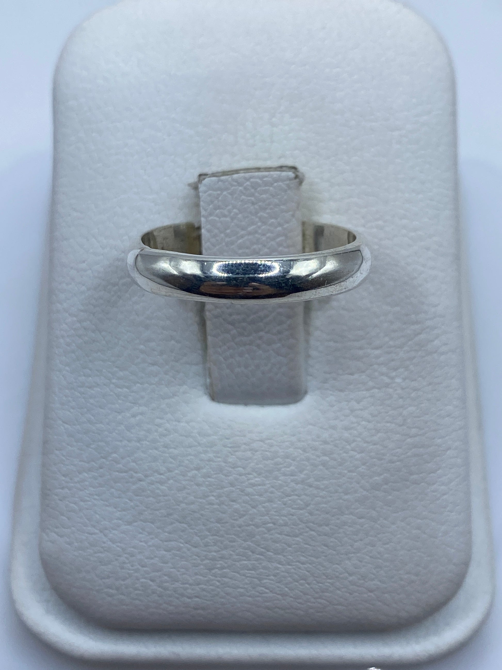 Anillo de plata banda lisa pulida en la mano de una mujer, mostrando su brillo minimalista