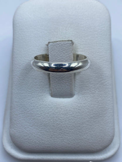 Anillo de plata banda lisa pulida en la mano de una mujer, mostrando su brillo minimalista