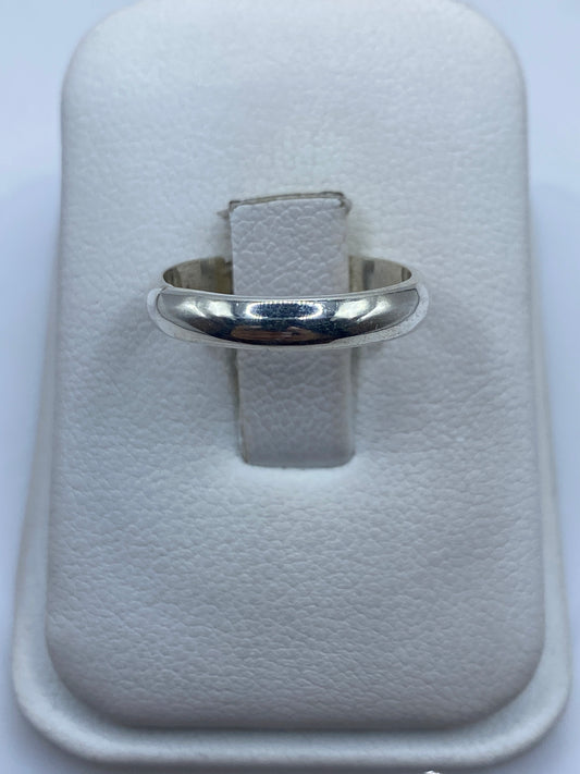Anillo de plata banda lisa pulida en la mano de una mujer, mostrando su brillo minimalista
