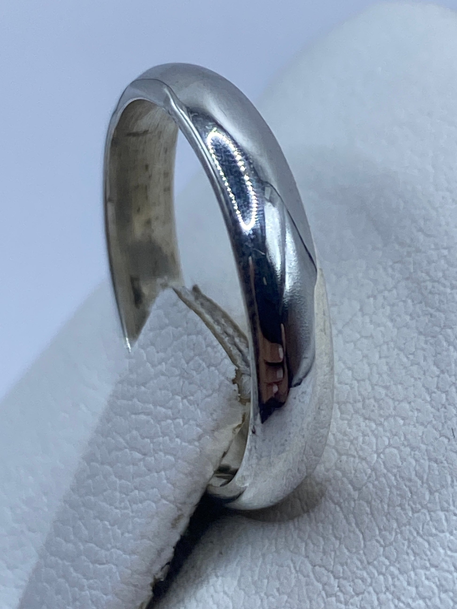 Anillo minimalista de plata sobre fondo blanco, diseño limpio y versátil