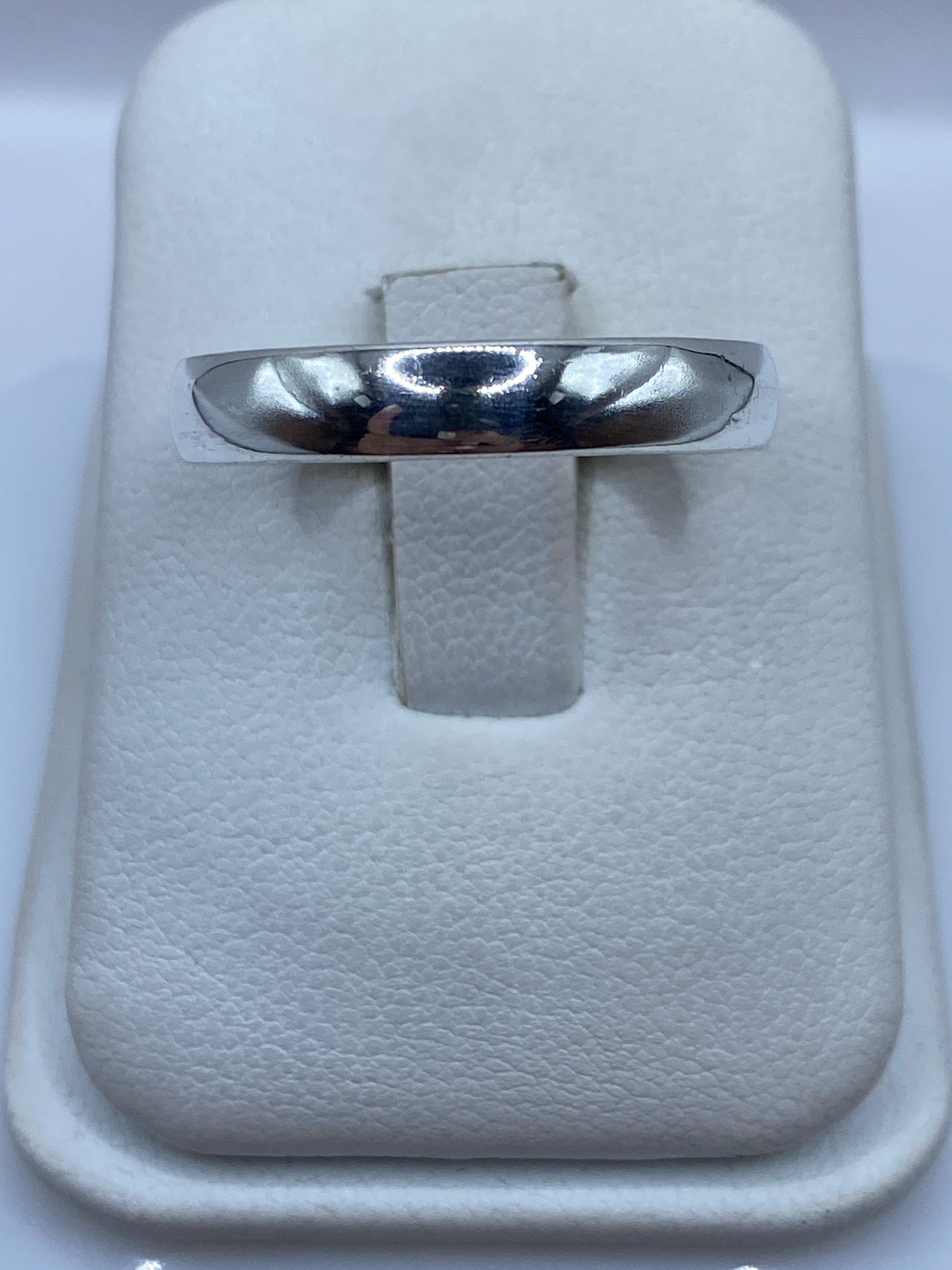 Anillo de plata banda pulida, minimalista, en el dedo de una mano