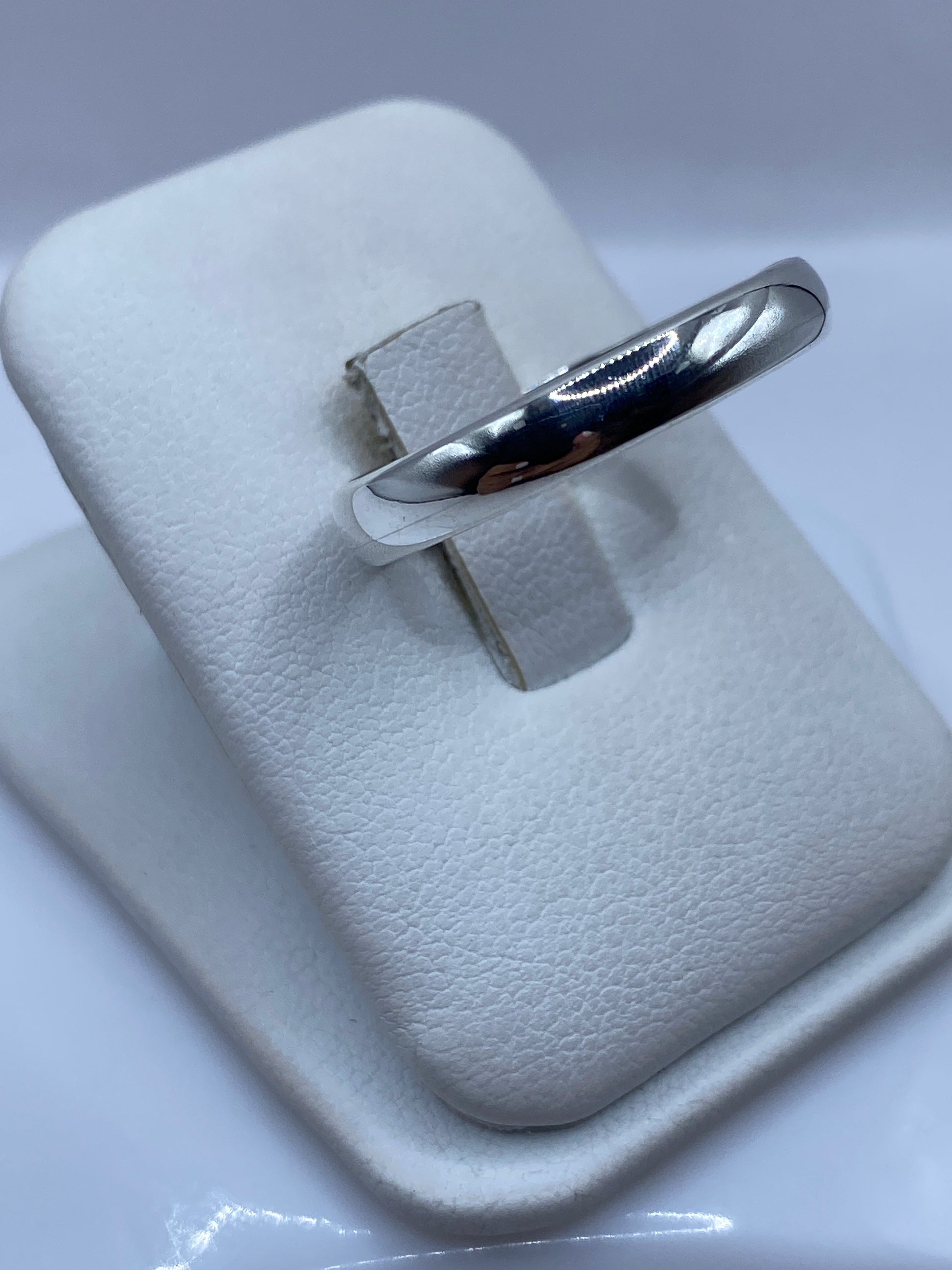 Anillo banda minimalista en dedo, mostrando pulido espejo y proporciones perfectas