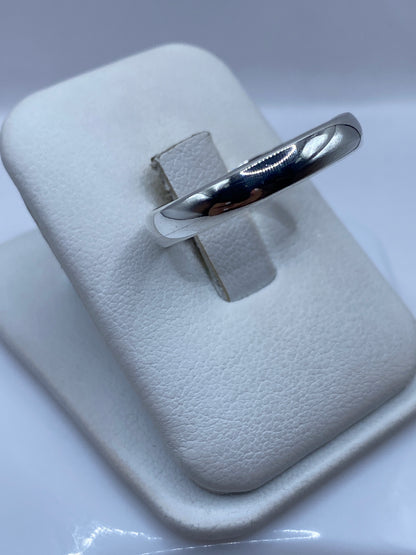 Anillo banda minimalista en dedo, mostrando pulido espejo y proporciones perfectas