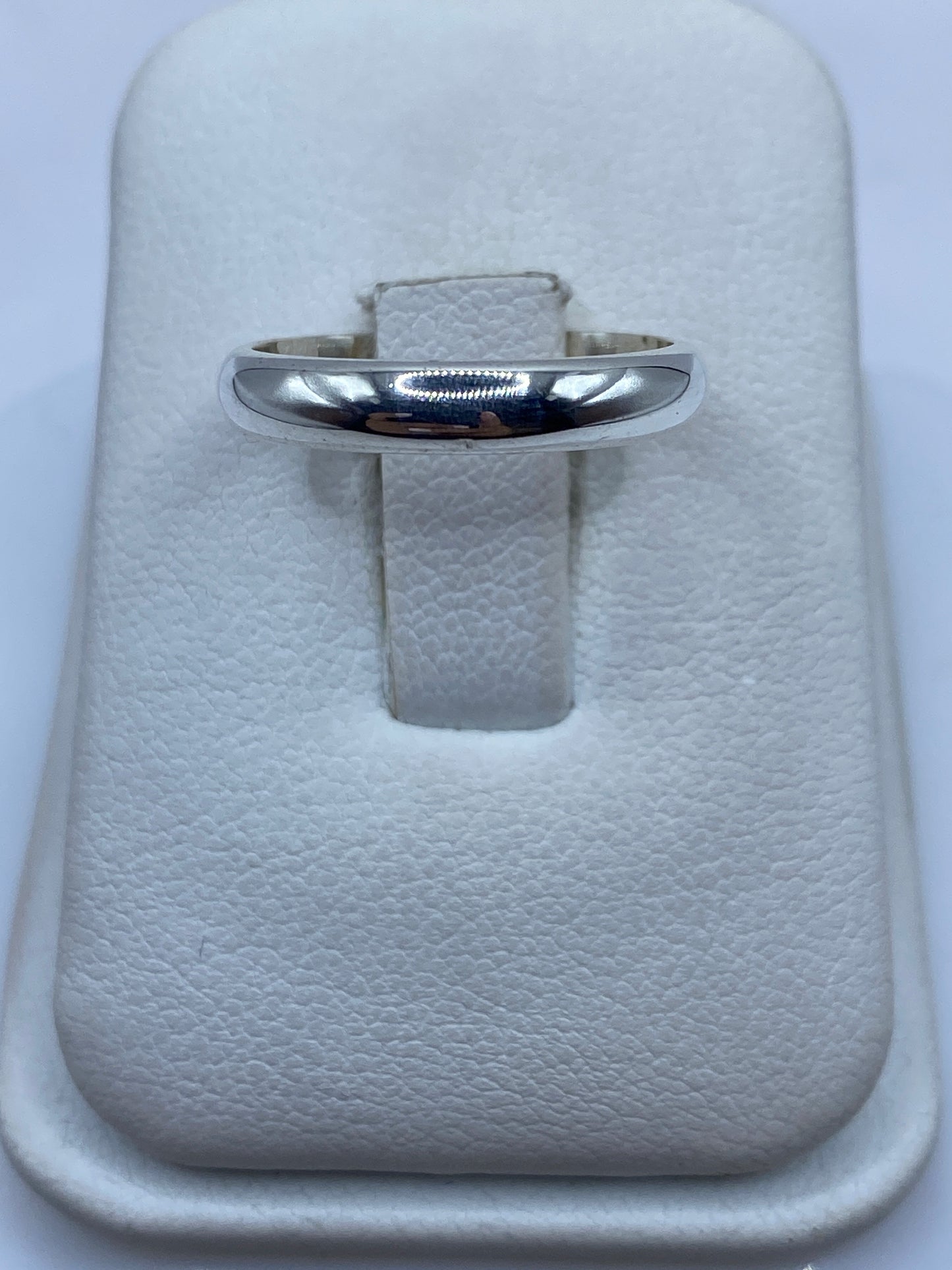Anillo de plata banda lisa pulida en la mano de una mujer con uñas naturales