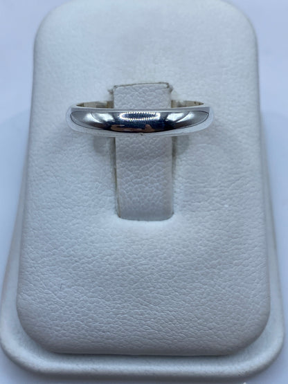 Anillo de plata banda lisa pulida en la mano de una mujer con uñas naturales