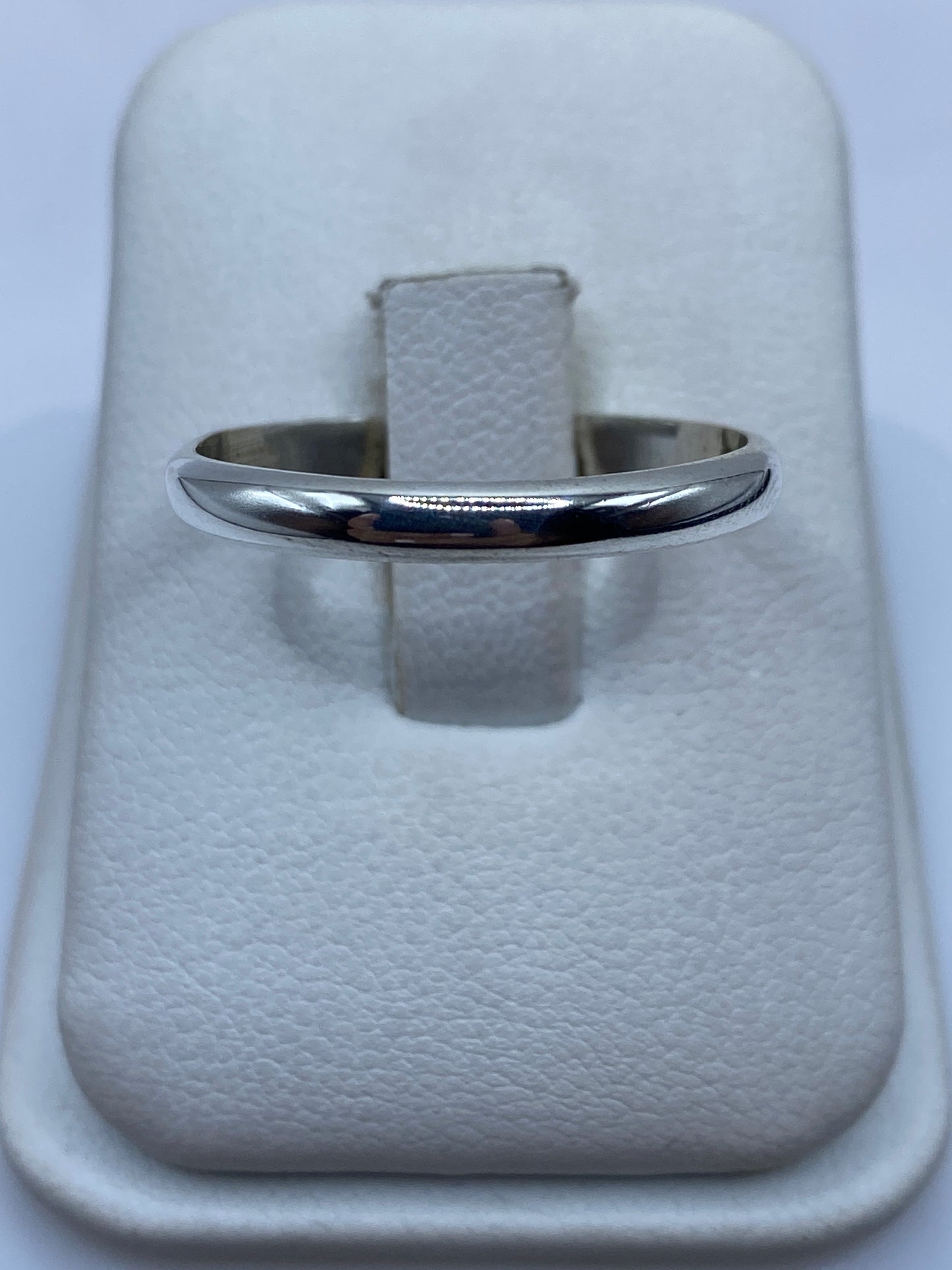 Anillo banda de plata .925 pulida, minimalista, en la mano sobre fondo blanco