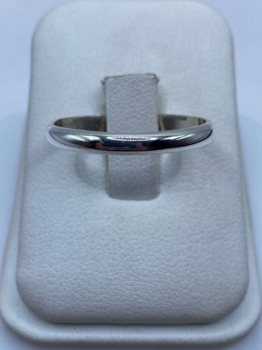 Anillo banda de plata .925 pulida, minimalista, en la mano sobre fondo blanco