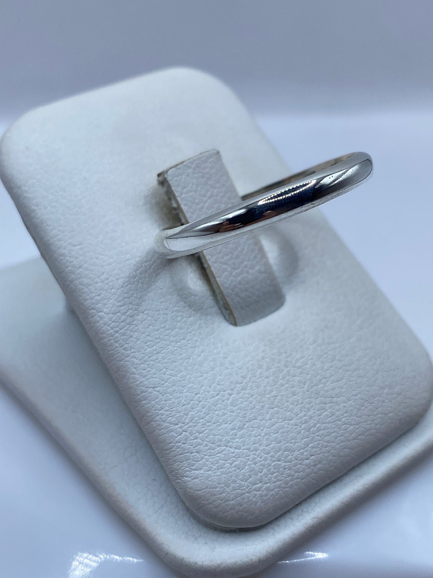 Vista lateral del anillo banda clásico de plata en envase de presentación