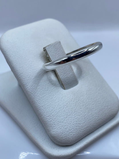 Vista lateral del anillo banda clásico de plata en envase de presentación