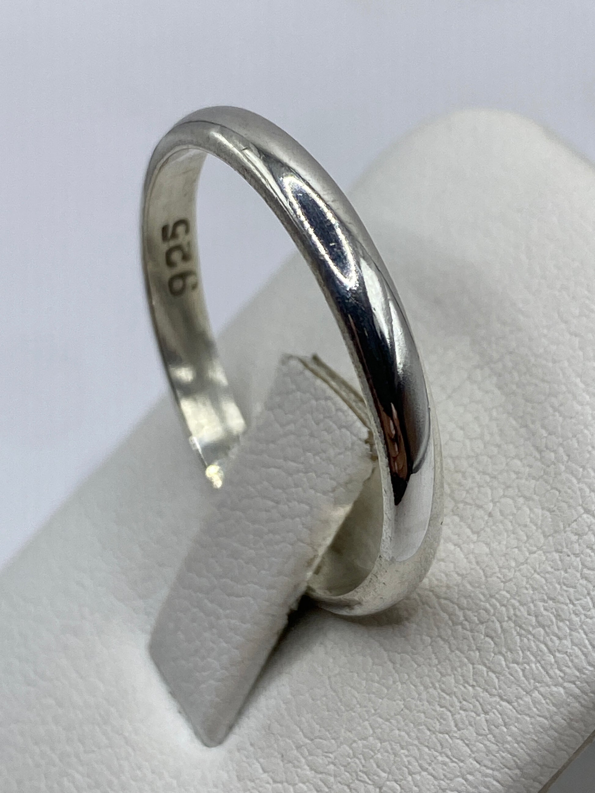 Anillo de plata lisa en dedo unisex, luz natural resaltando el brillo