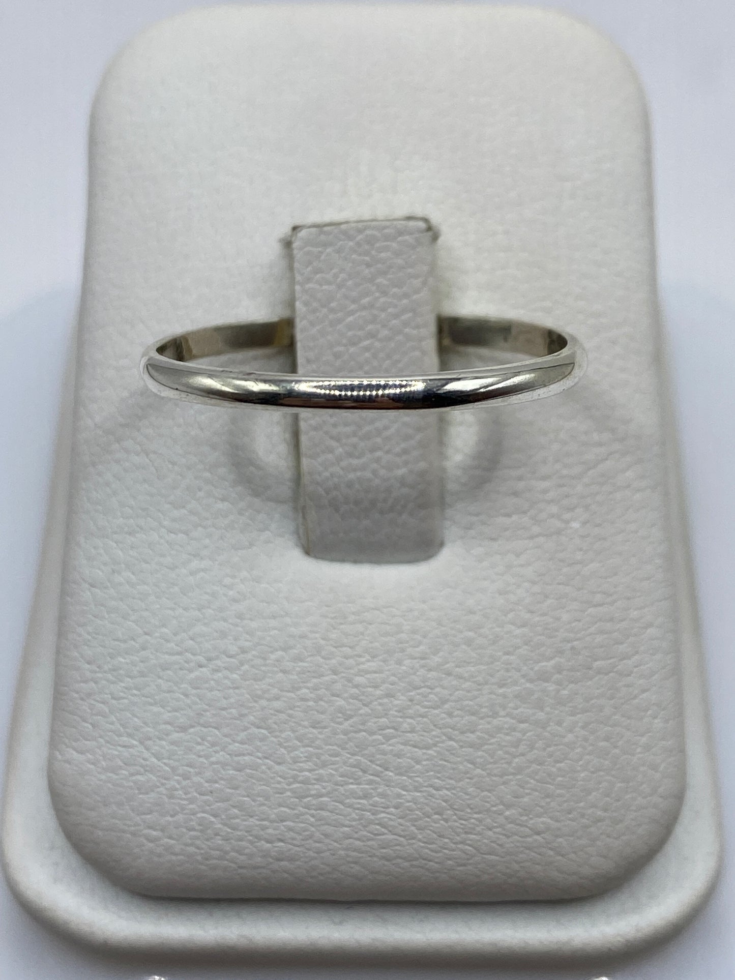 Anillo banda de plata .925 pulida en la mano, luz reflejada en el acabado