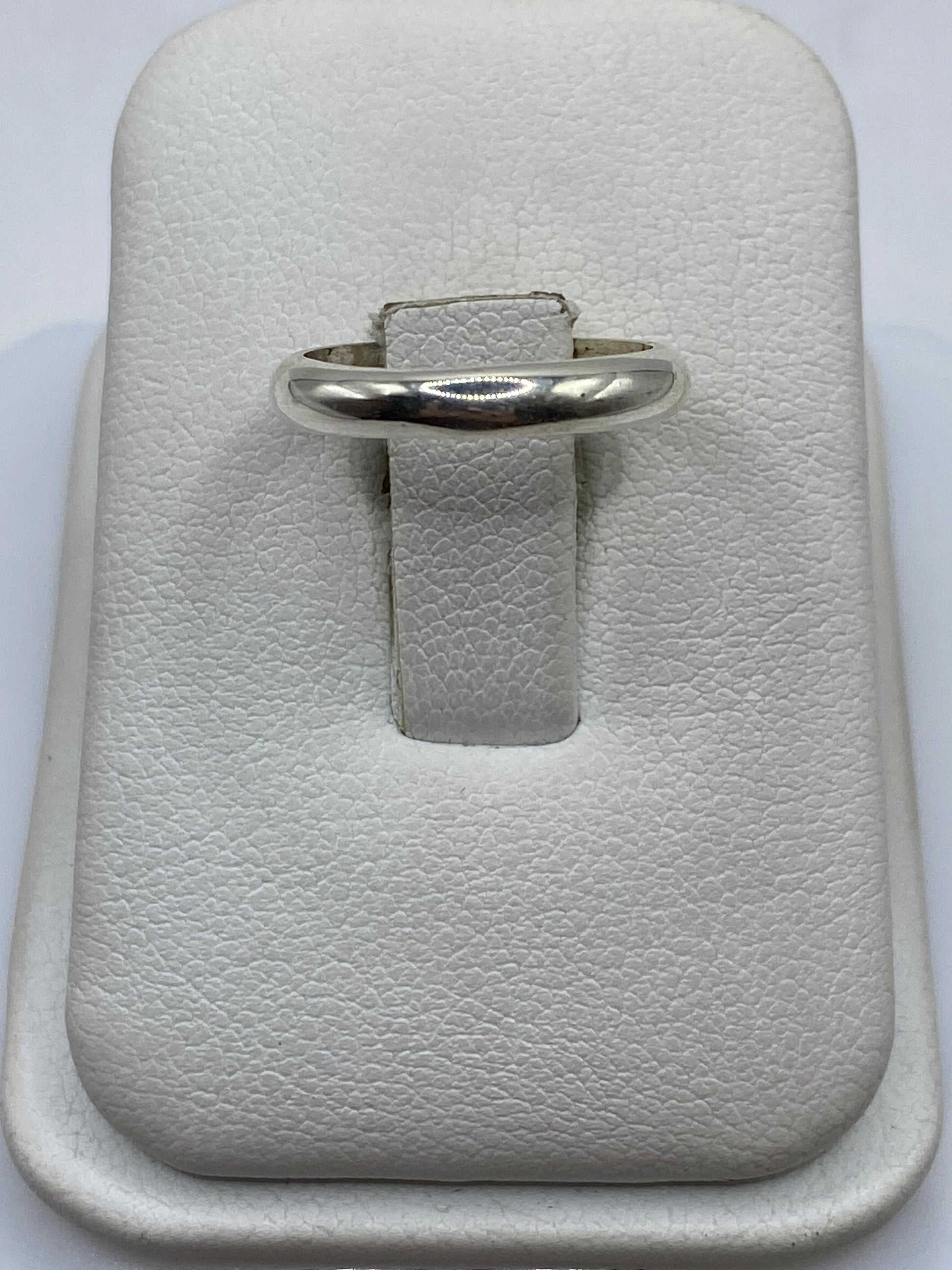 Anillo de plata .925 banda lisa pulida en la mano de una mujer con acabado espejo