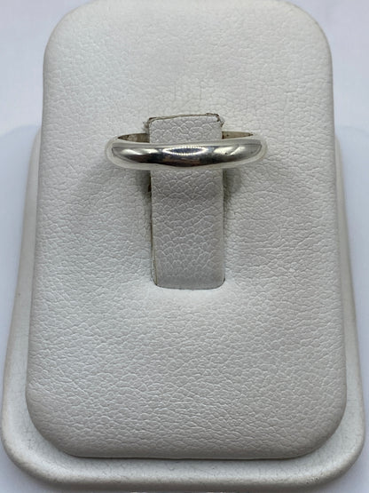 Anillo de plata .925 banda lisa pulida en la mano de una mujer con acabado espejo