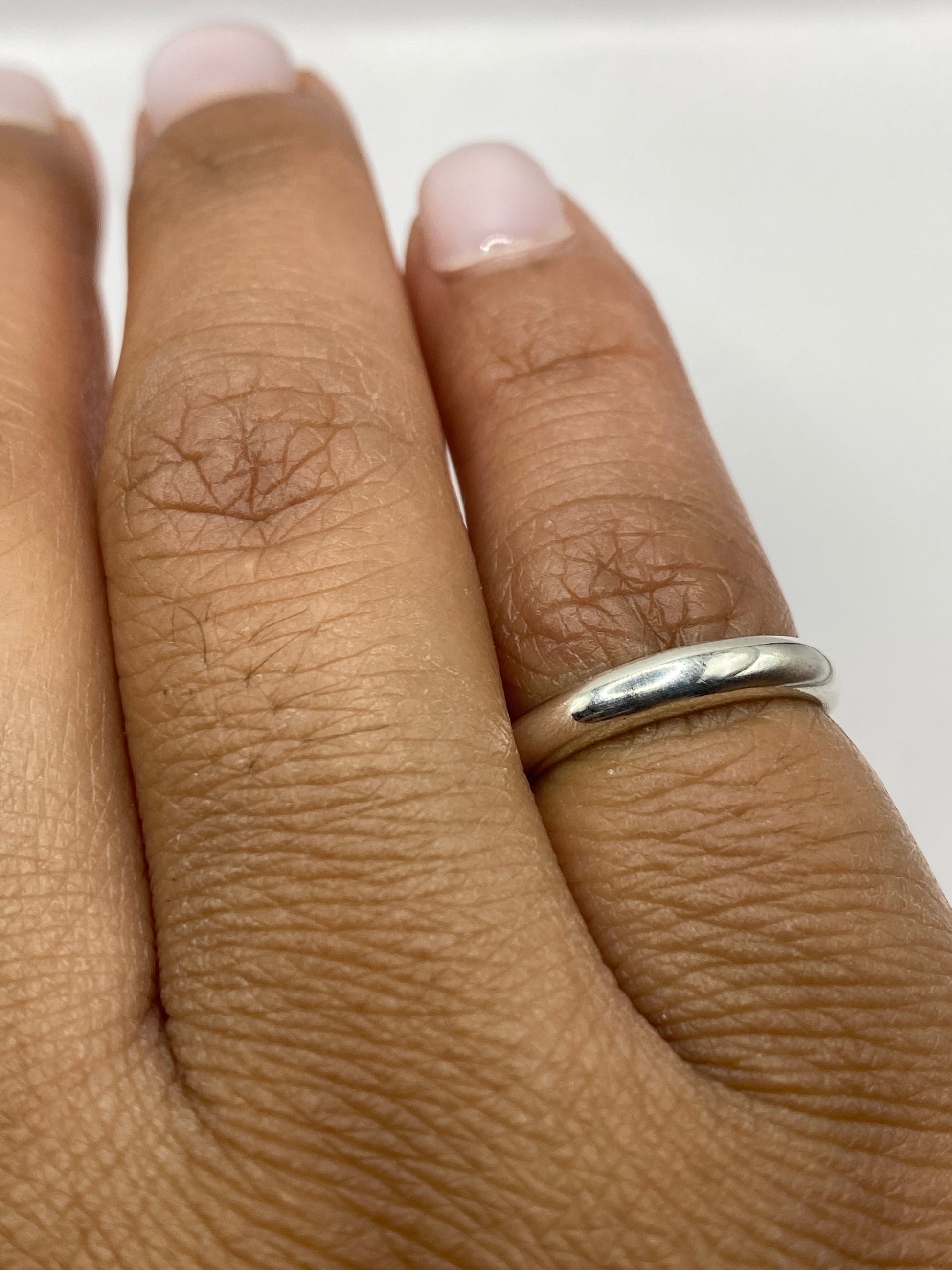 Anillo banda de plata sobre fondo blanco mostrando la pureza del acabado