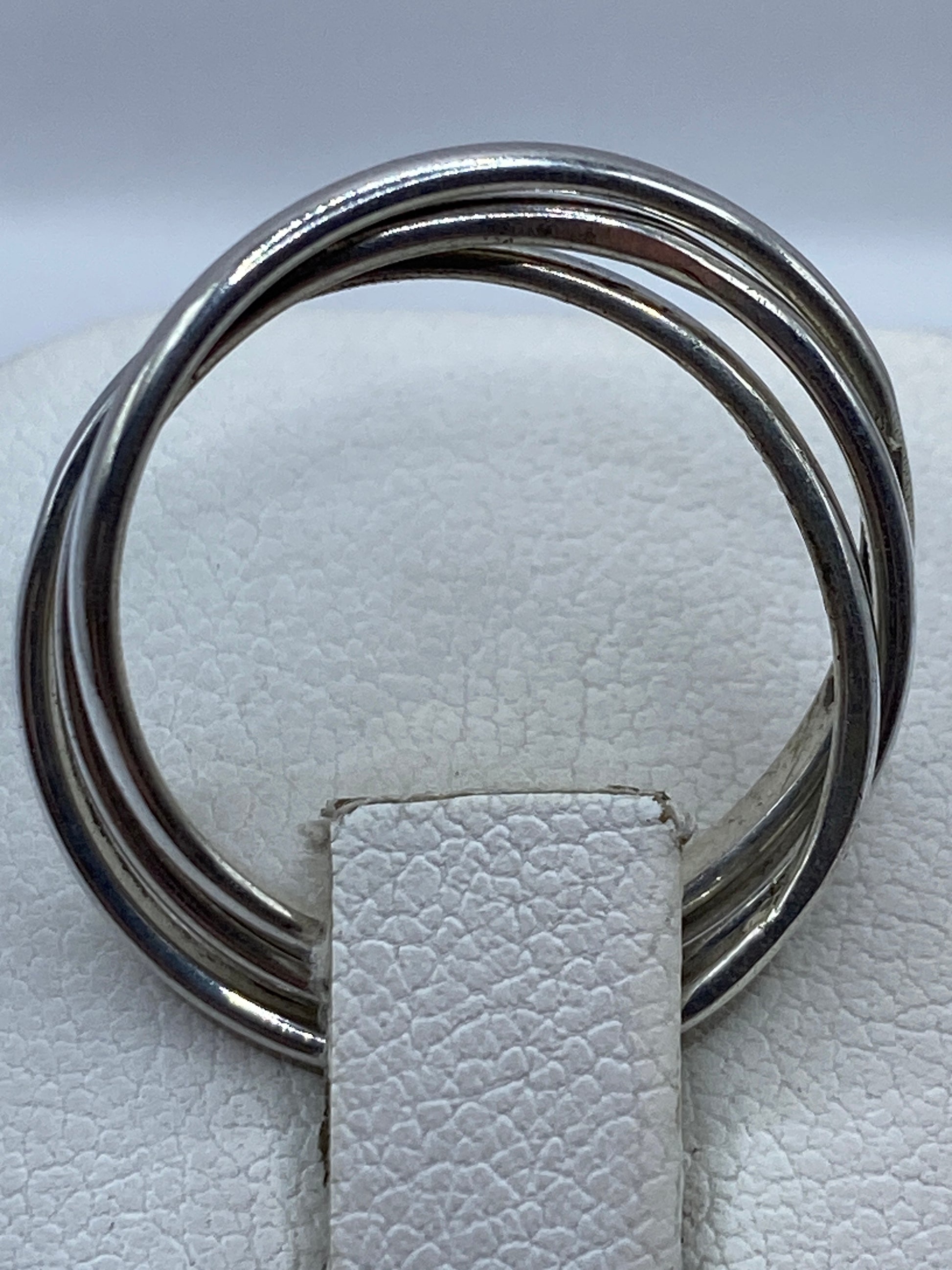 Detalle frontal del anillo con eslabones entrelazados sobre fondo blanco