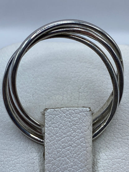 Detalle frontal del anillo con eslabones entrelazados sobre fondo blanco
