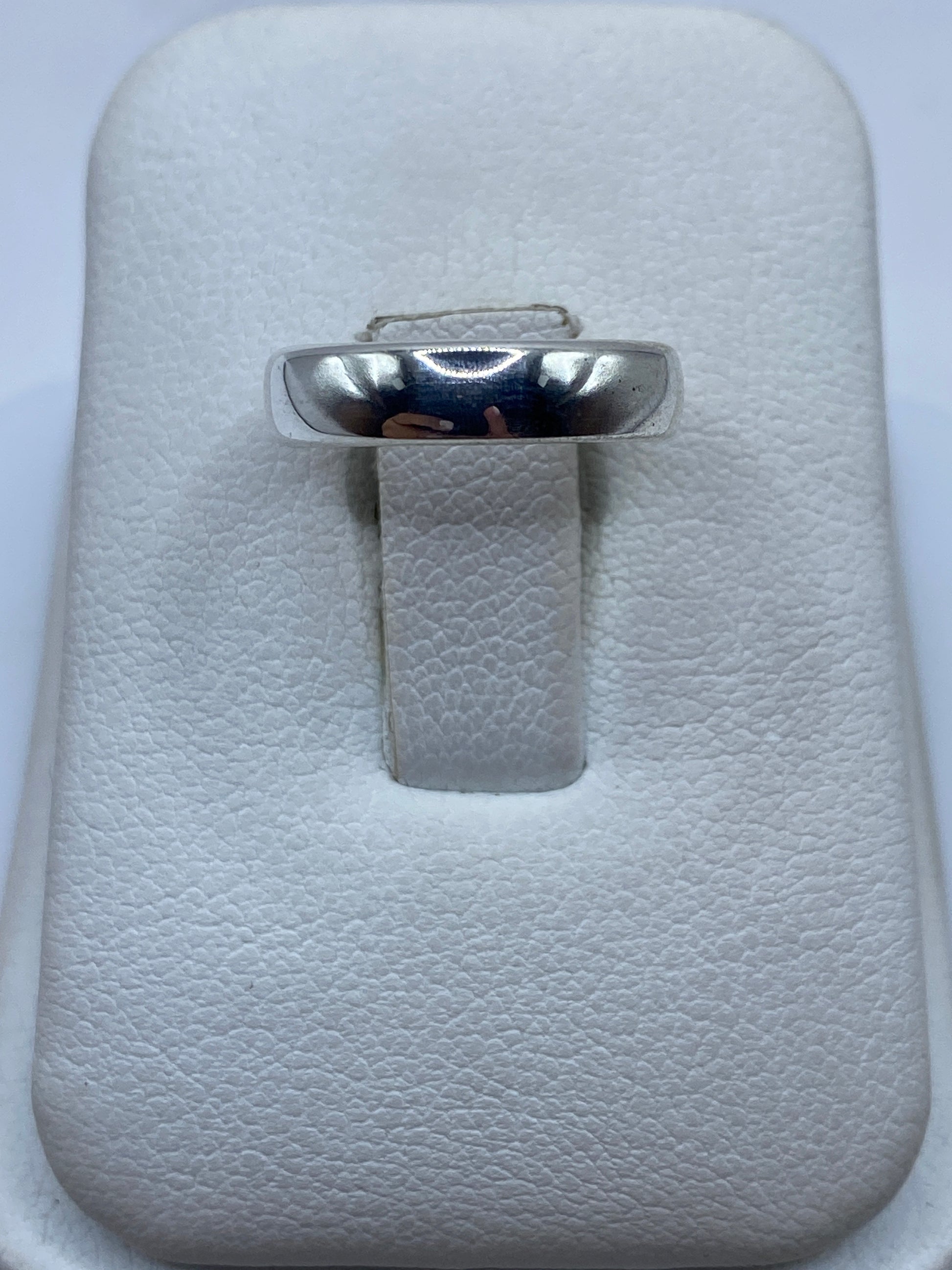 Anillo de plata pulida minimalista en estuche blanco, vista superior