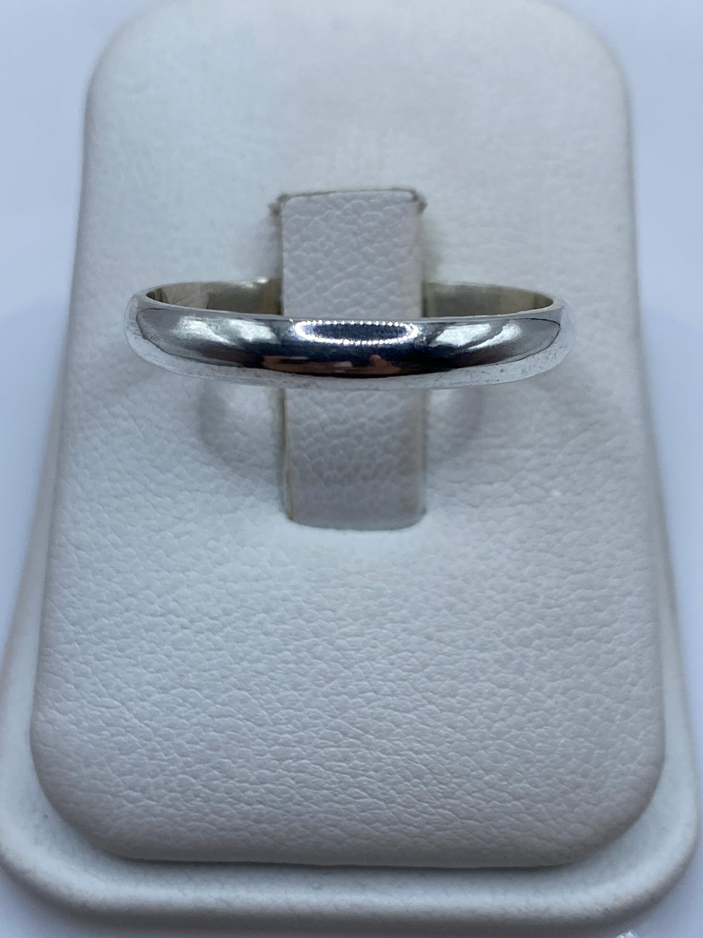 Anillo de plata banda pulida minimalista en estuche blanco mostrando el brillo espejo