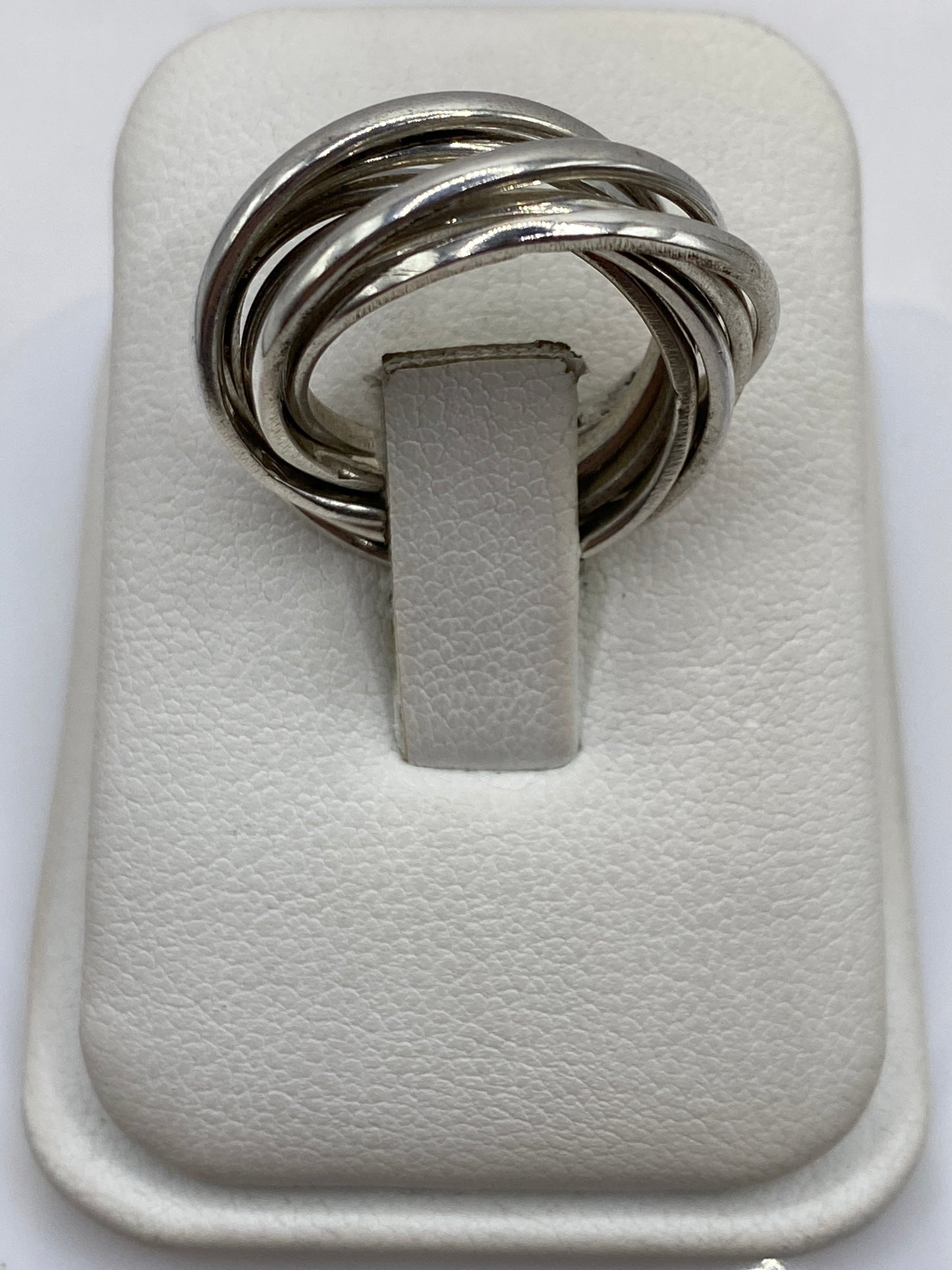 Anillo de plata con eslabones entrelazados en la mano de una mujer