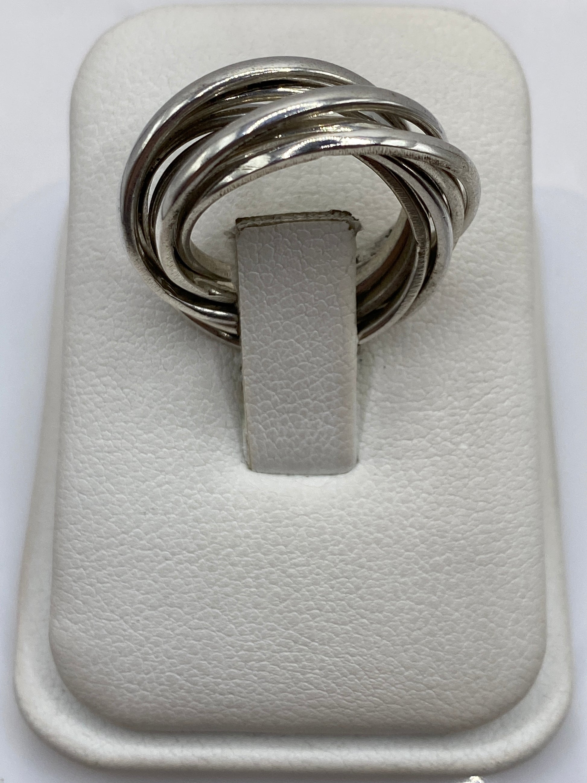 Anillo de plata con eslabones entrelazados en la mano de una mujer