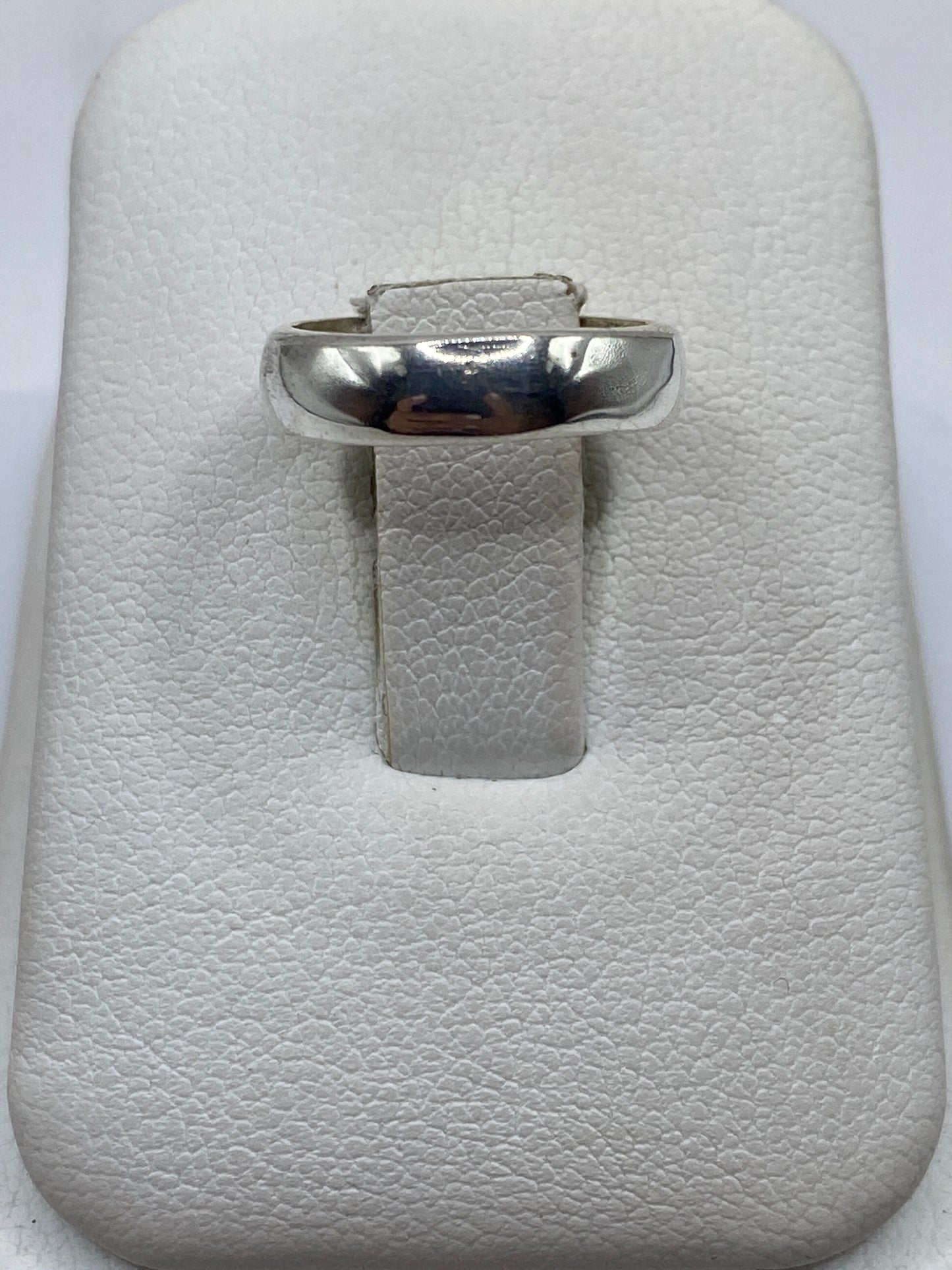 Anillo de plata banda pulida en la mano, vista superior mostrando el brillo espejo
