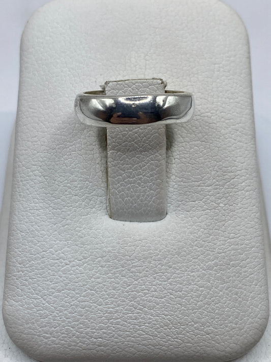 Anillo de plata banda pulida en la mano, vista superior mostrando el brillo espejo