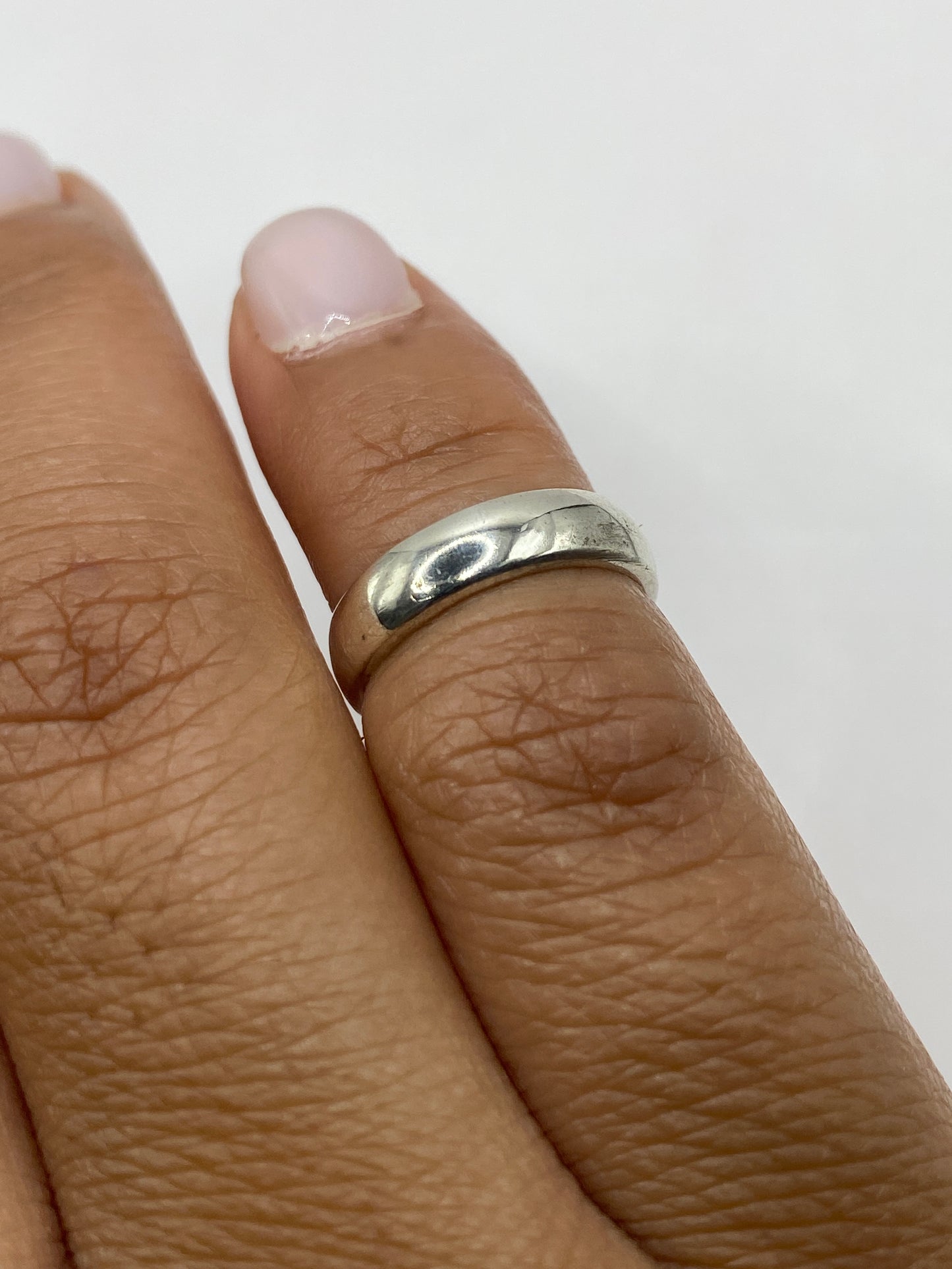 Anillo de plata pulida en la mano de una mujer, uso diario minimalista