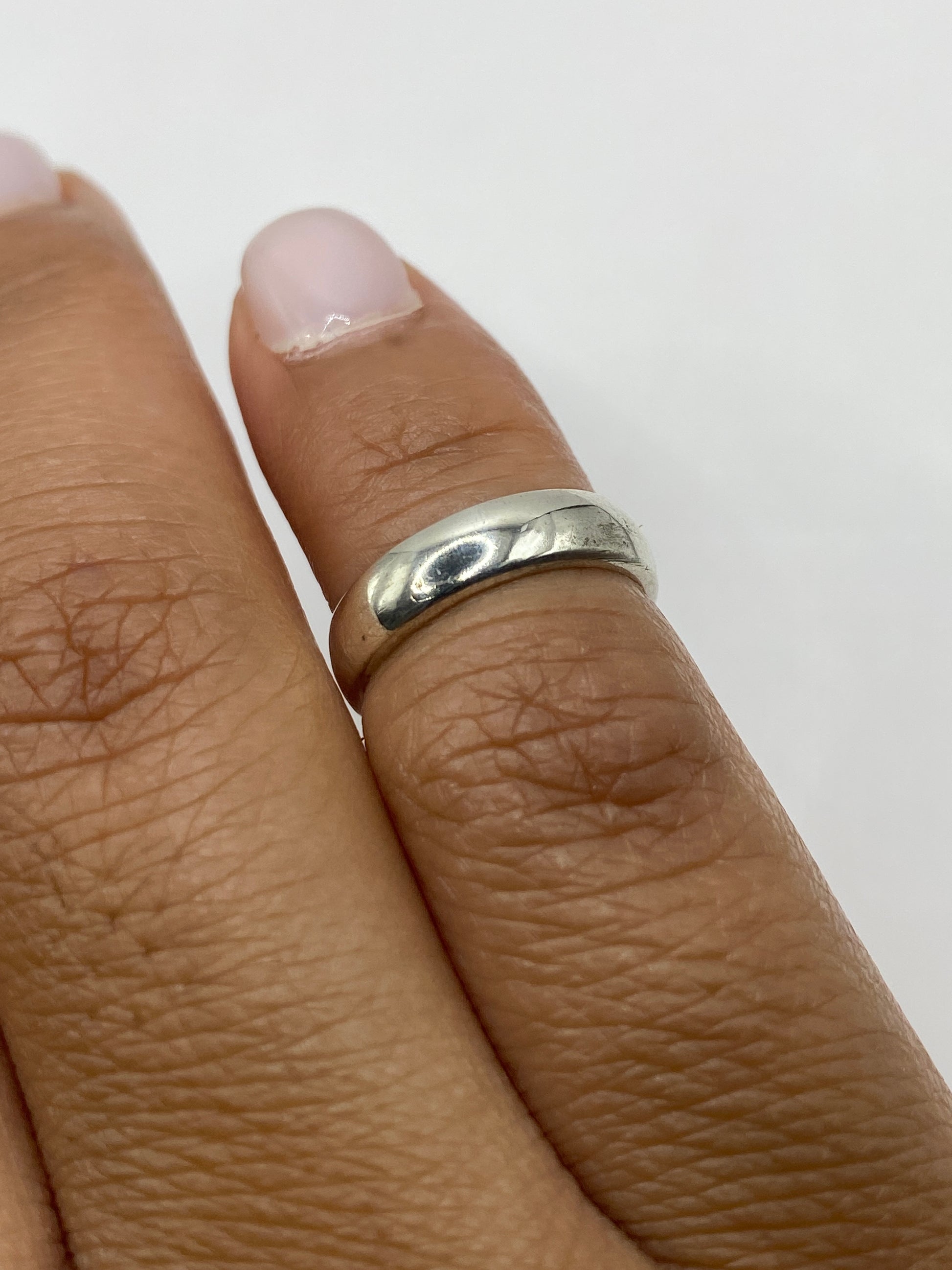 Anillo de plata pulida en la mano de una mujer, uso diario minimalista