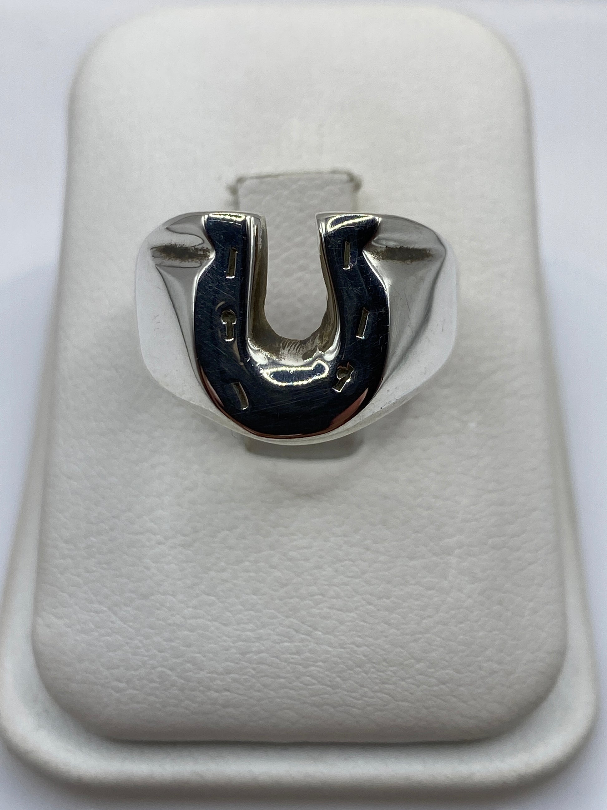 Anillo herradura de plata .925 maciza en la mano de un hombre, frente brilla