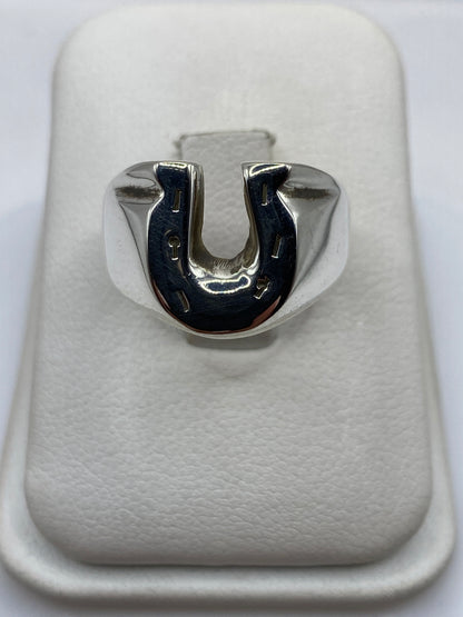 Anillo herradura de plata .925 maciza en la mano de un hombre, frente brilla