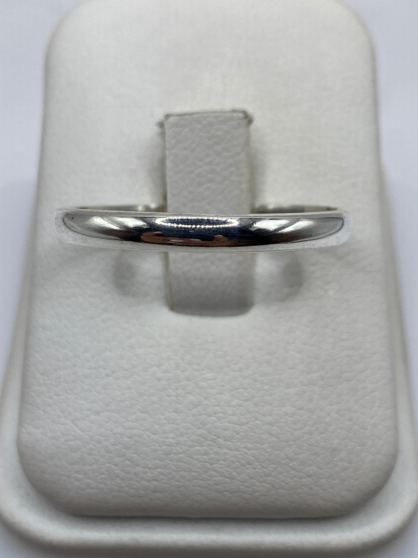 Anillo de plata pulida minimalista en mano de hombre mostrando el acabado espejo