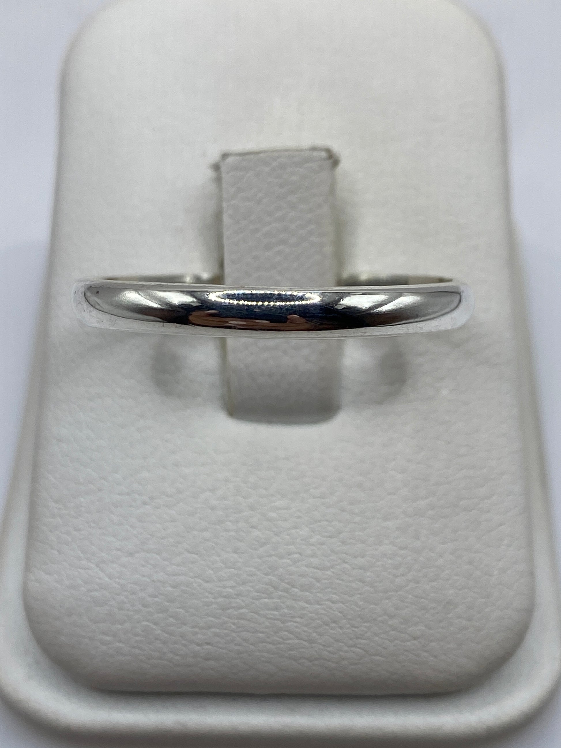 Anillo de plata pulida minimalista en mano de hombre mostrando el acabado espejo